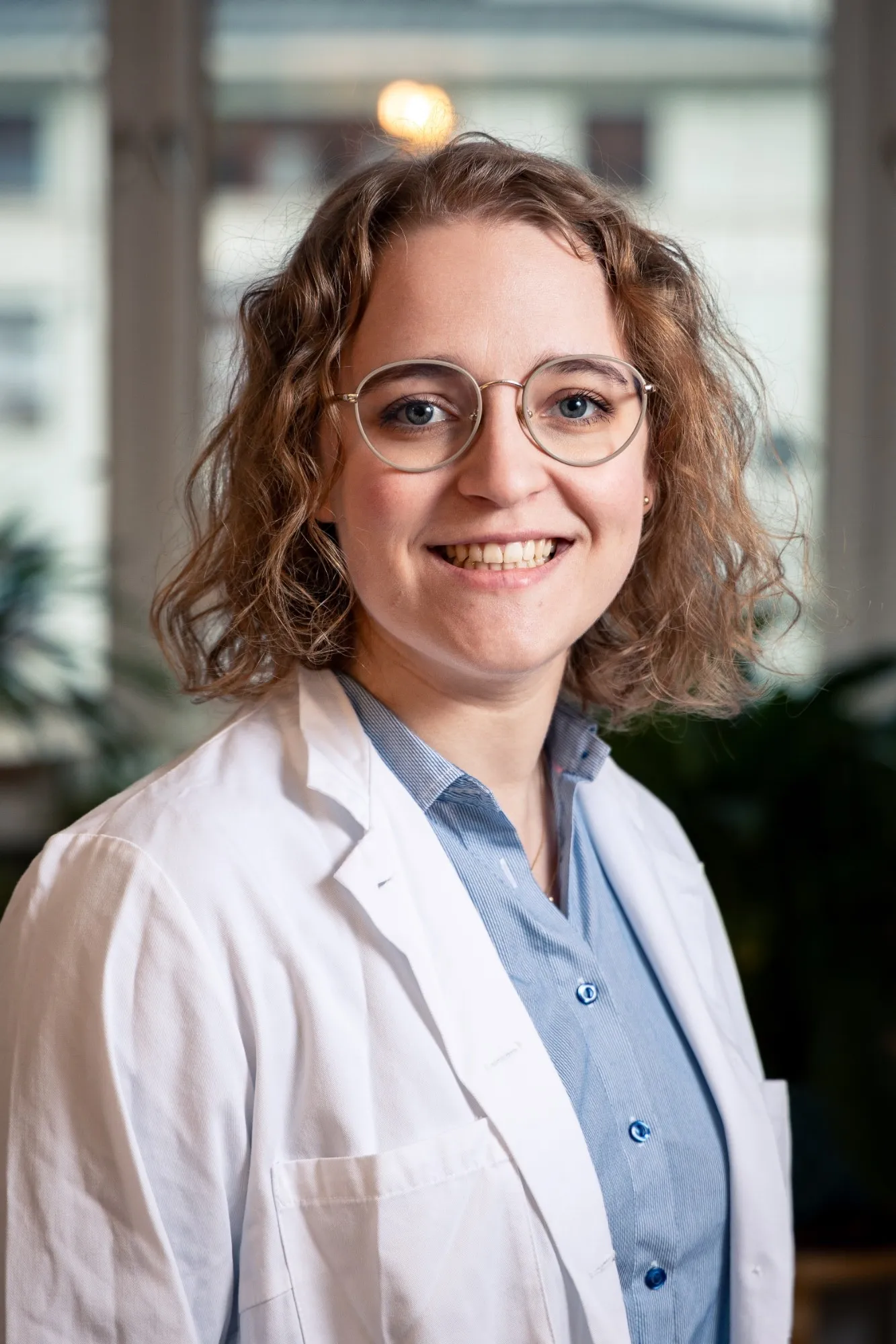 Alexandra Dahlberg in a white doctor’s coat and blue shirt, smiling